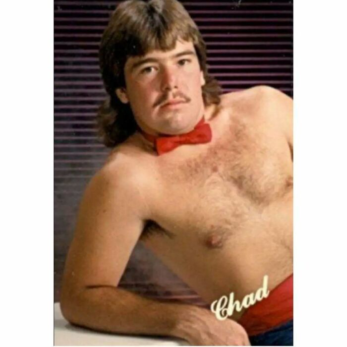 Shirtless man with mustache and mullet wearing a red bow tie posing in a retro styled photo embodying old school cool dads.