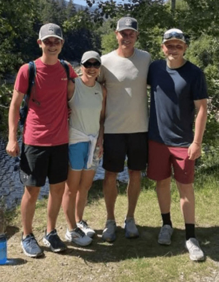 Group of four casually dressed people posing outdoors near a river, representing Coldplay fan who exposed cheating CEO at concert.
