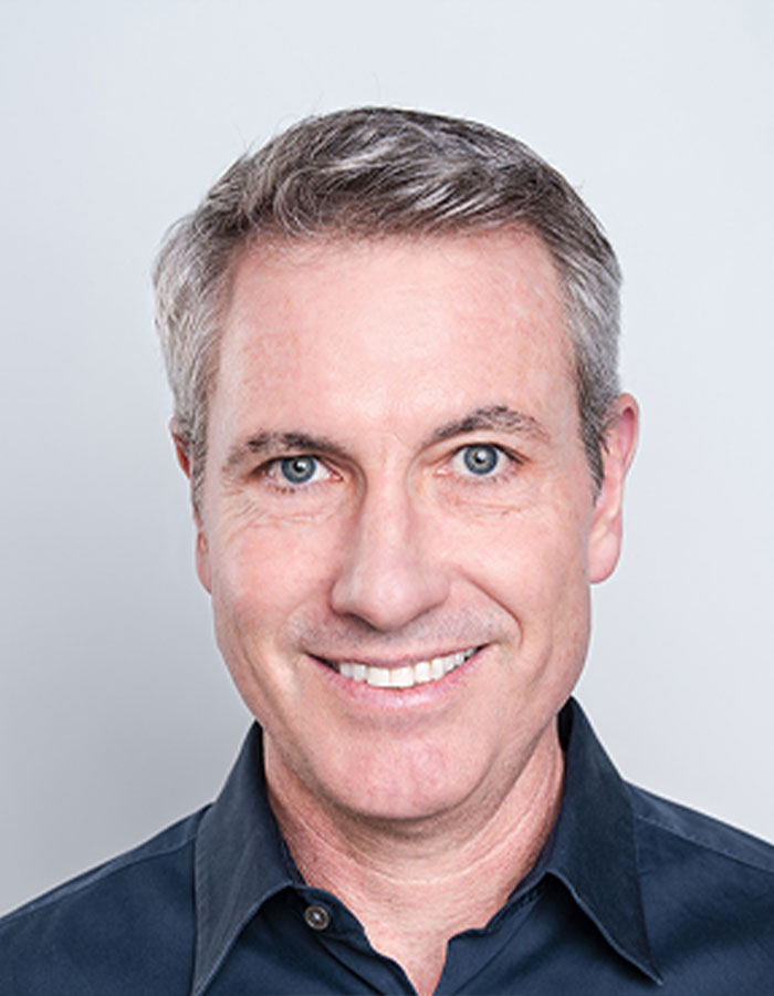 Middle-aged man smiling in a dark shirt, representing Coldplay fan who exposed cheating CEO by filming kiss cam.