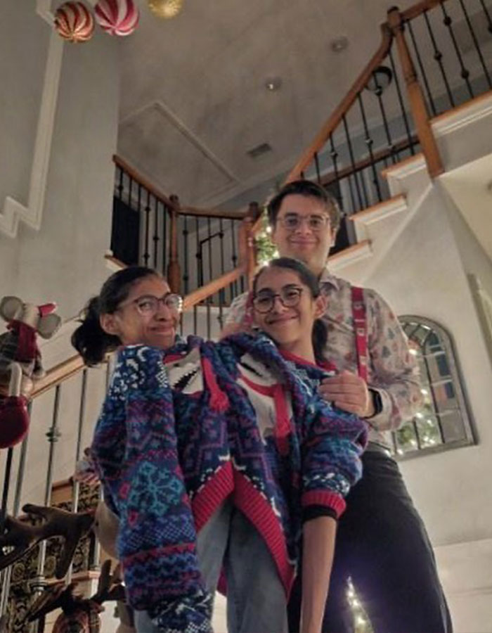 Conjoined twin influencer wearing colorful sweater with boyfriend in a cozy home setting by staircase during intimate moment