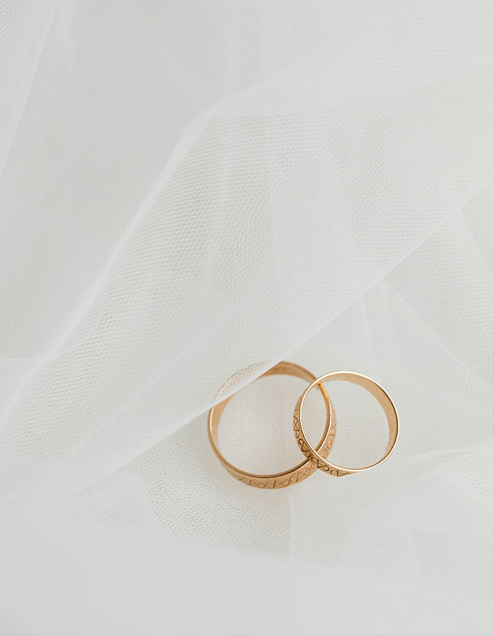 Two gold wedding rings resting on soft white fabric, symbolizing a conjoined twin influencer's intimate wedding ceremony.