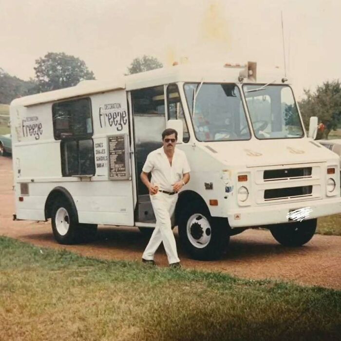 Vintage dad in white outfit confidently posing beside an old school cool ice cream truck on a sunny day.