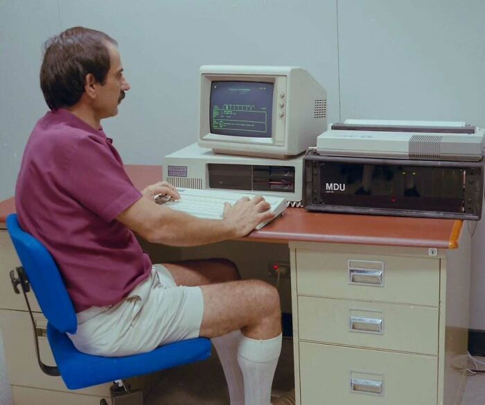 Man in vintage outfit using an old computer, showcasing old school cool style from dads of the past.