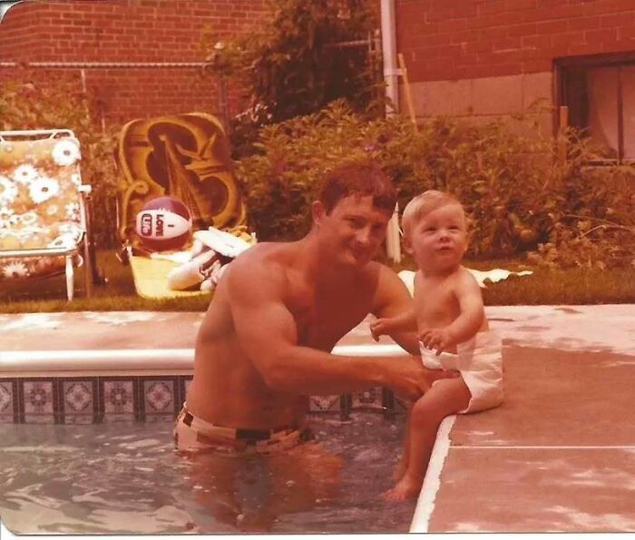 Vintage photo of an old school cool dad in a pool holding his toddler child on the edge of the pool.