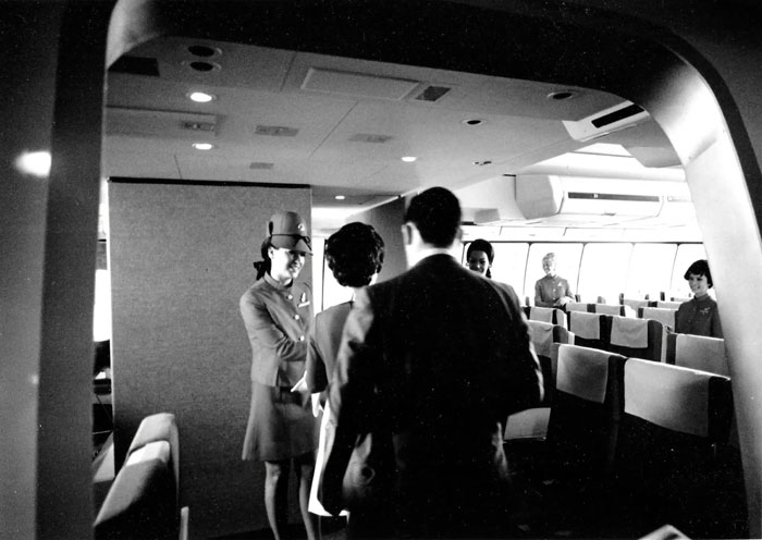 Vintage black and white photo of airline crew and passengers inside airplane cabin from decades of FBI dead ends investigation.