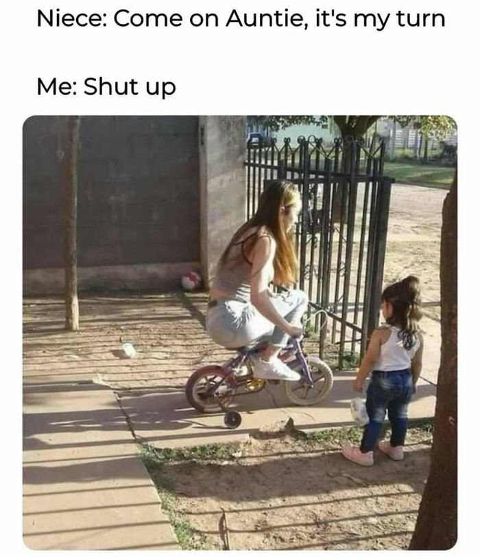 Woman riding a small bike with training wheels while a little girl watches in a funny memes scene about not taking life seriously.