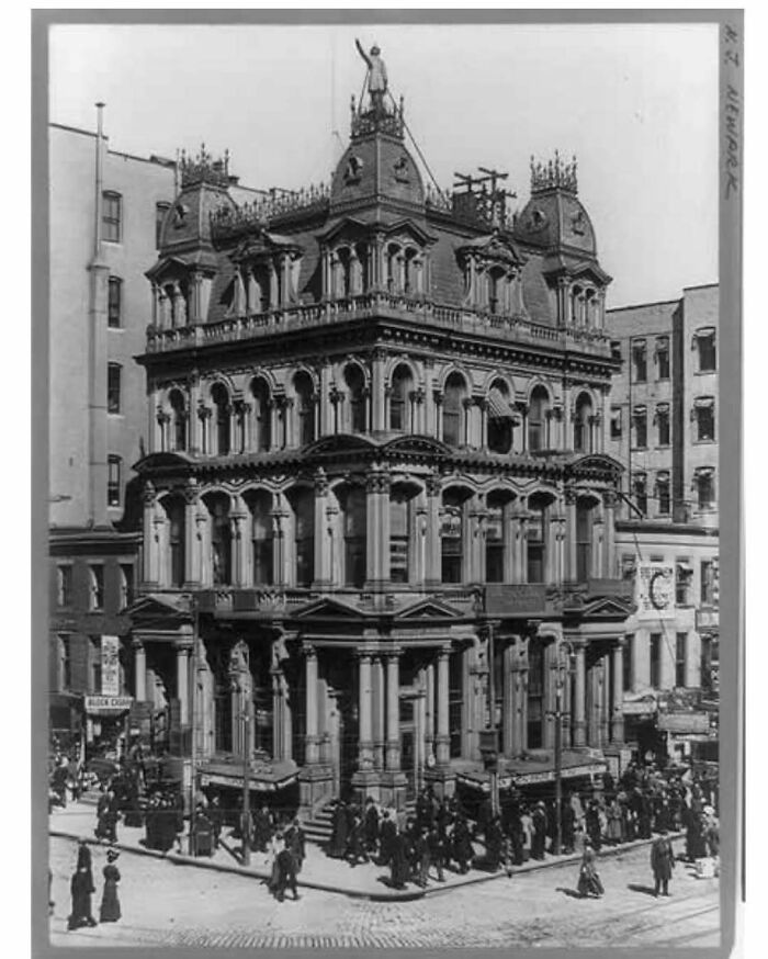 Historic old architecture building with intricate details and crowds gathered around on city streets.