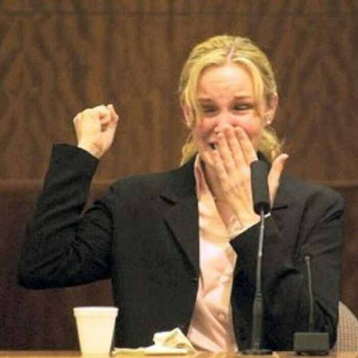 Woman in a courtroom raising fist and covering mouth in surprise, illustrating interesting facts that might surprise viewers.