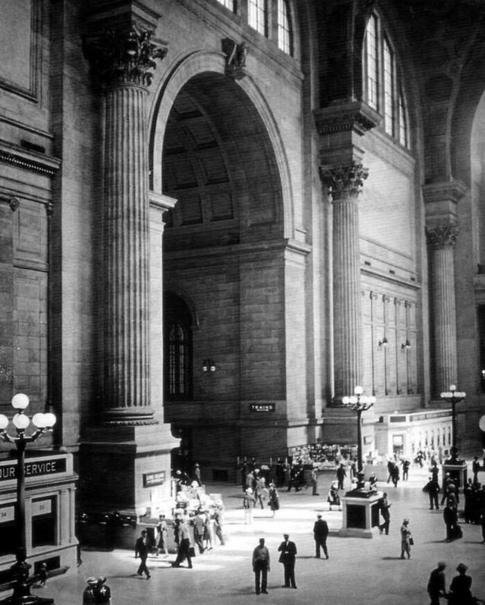 Interior view of old architecture featuring grand arches and columns in a historic public building with people walking.
