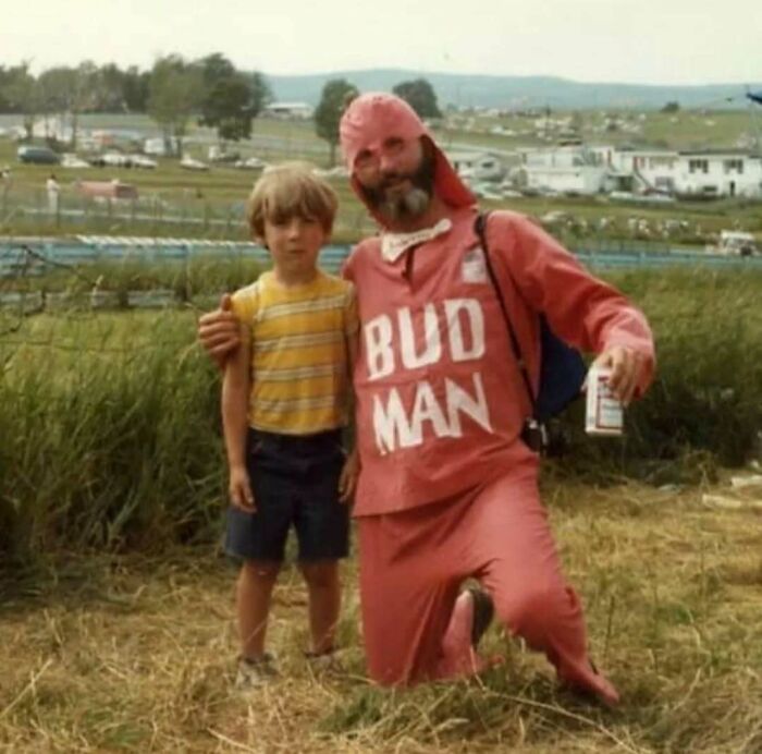 Vintage photo of a dad in a Bud Man costume with his son, showcasing old school cool dads from the past outdoors.