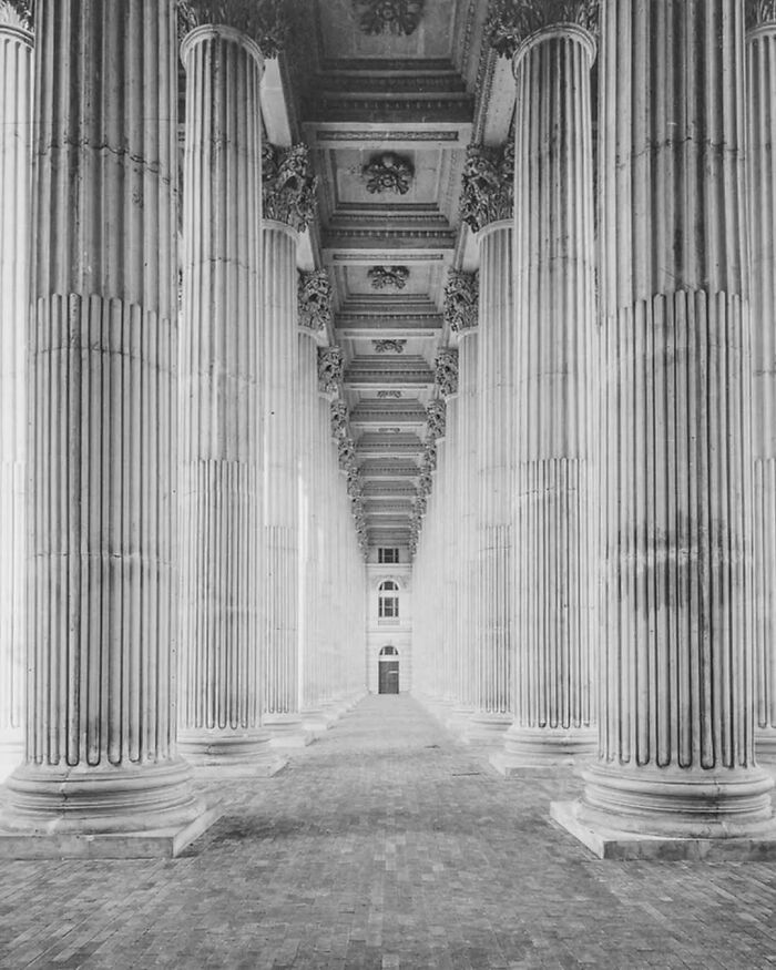 Rows of tall, ornate columns in old architecture showcasing the beauty and grandeur of the past in black and white.