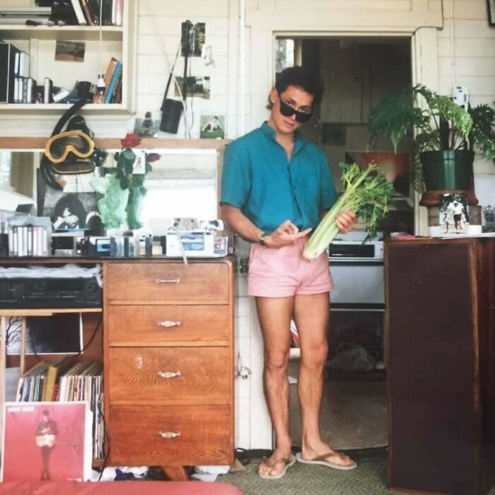 Young man in retro outfit wearing sunglasses and holding celery, showcasing old school cool vibes from past dads.