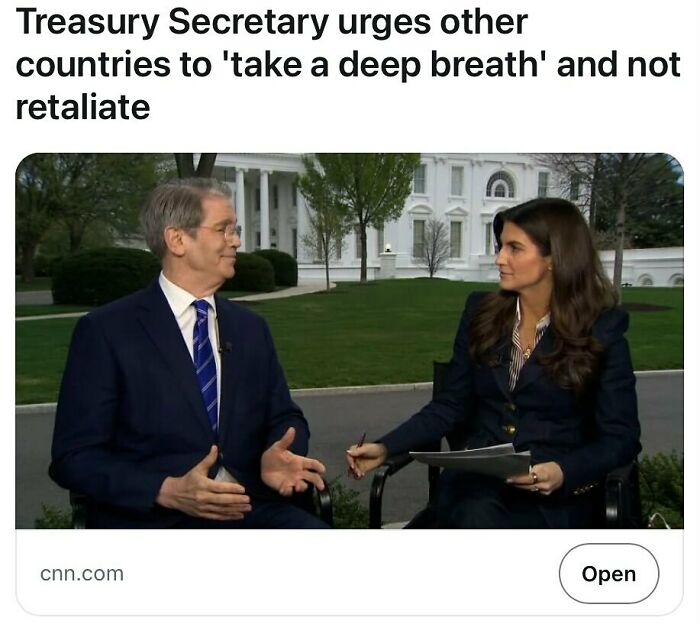 Two people seated outdoors near a government building discussing headlines that could pass for satire but are true.