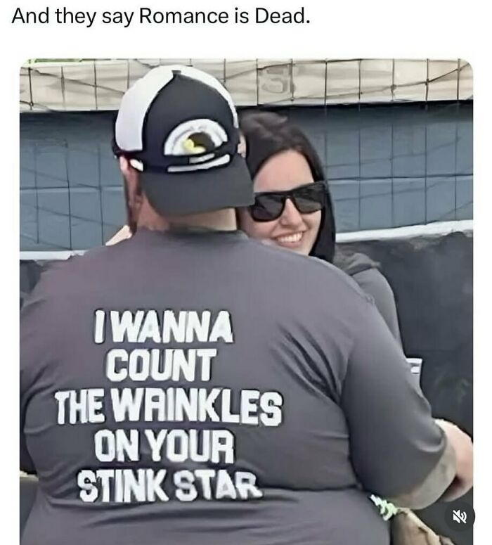 Couple smiling and embracing with a man wearing a funny shirt, showcasing random and chaotic memes that are unexpectedly funny.