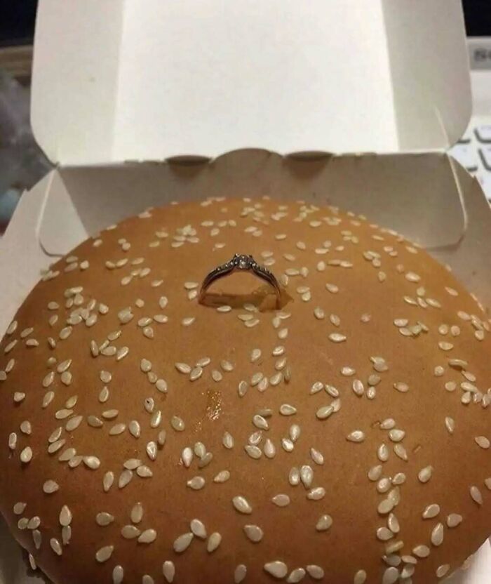 Sesame seed burger bun with a diamond ring embedded in the center creating a confusing and intriguing picture.