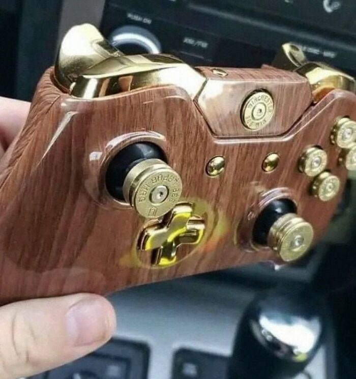 Wooden and gold game controller with bullet shell buttons, a bizarre design that makes no sense but captivates attention.