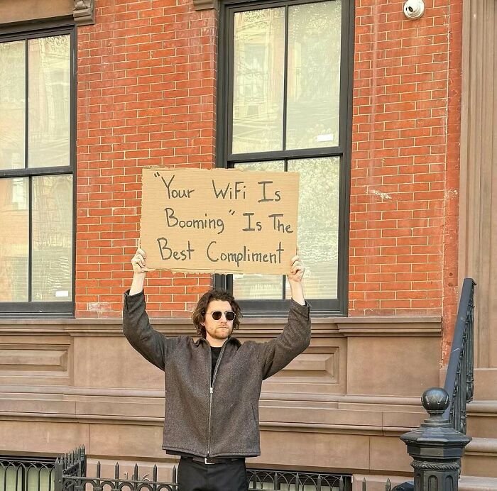 Man holding a cardboard sign with a witty message about WiFi, representing Dude With The Sign humor and social commentary.