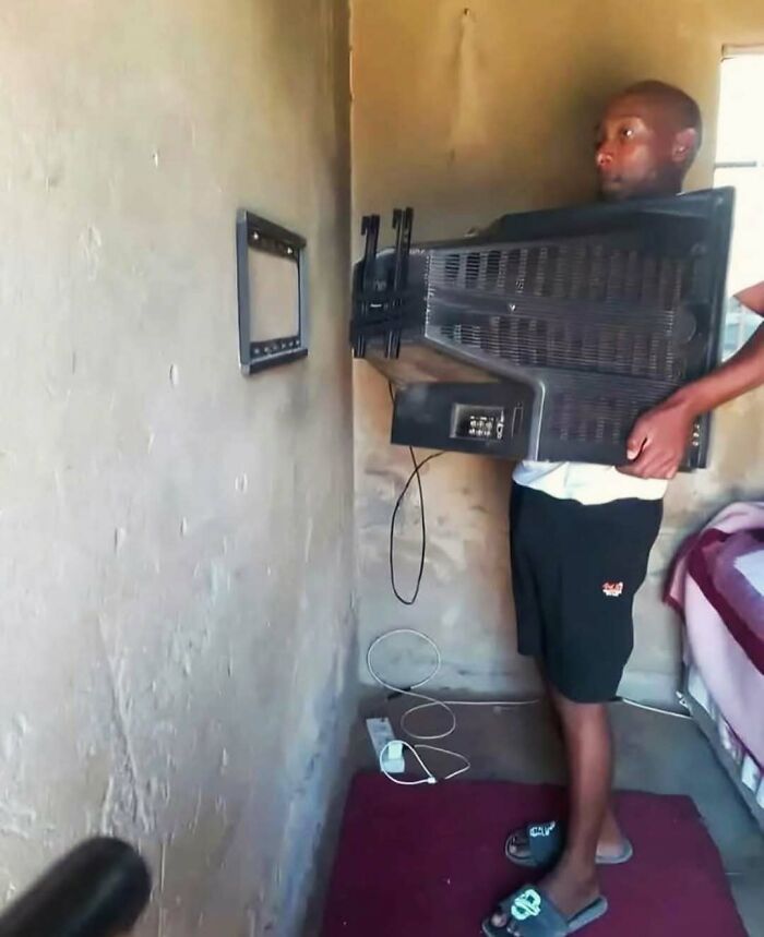 Man trying to mount old TV to wall bracket in a way that makes no sense, a picture full of confusion and humor.