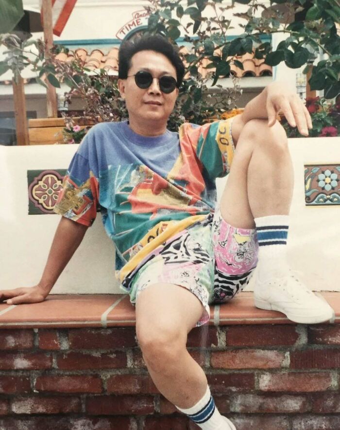 Man wearing colorful vintage clothes and sunglasses sitting outdoors, showcasing old school cool dads style from the past.