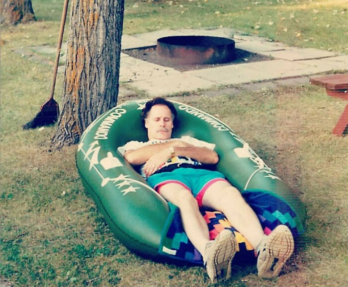 Man embodying old school cool dads from the past, relaxing outdoors on an inflatable lawn chair on grass.