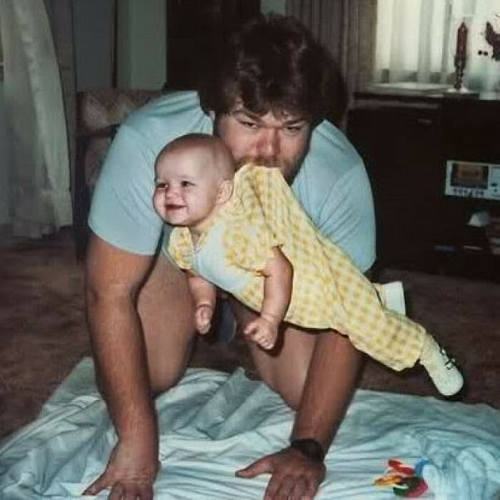 Dad from the past playfully holding a smiling baby, capturing the essence of old school cool fatherhood moments.