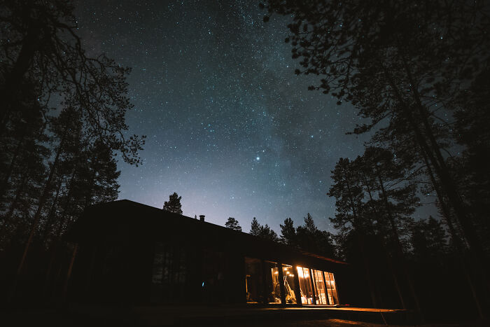 Cabin in the woods at night with glowing windows under a starry sky, offering a peaceful and true home retreat. - 14