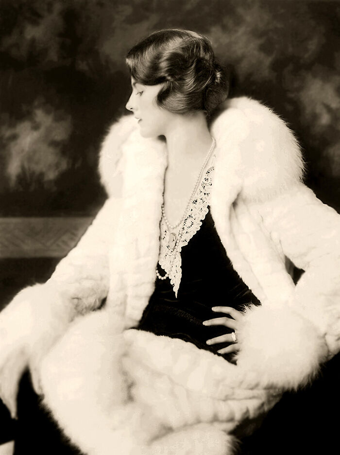 Vintage portrait of a woman showcasing timeless beauty, dressed in elegant fur with classic 1920s hairstyle and pearls.