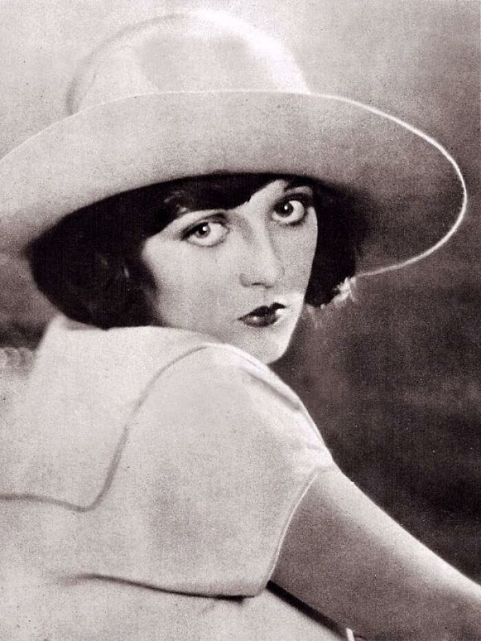 Vintage portrait of a woman wearing a wide-brimmed hat, showcasing timeless beauty in a century-old photo.