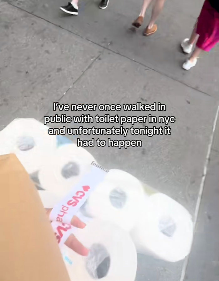 Person walking on sidewalk carrying a pack of toilet paper, highlighting influencer ashamed to buy toilet paper.