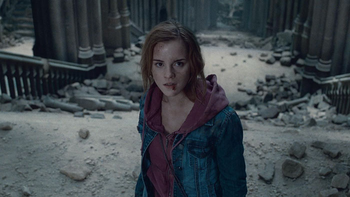 Emma Watson standing in a ruined building with dust and debris, looking determined amid major legal trouble news. - 2
