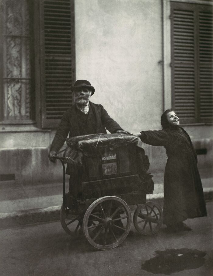 19th century invaluable photo showing a man with a cart and a child holding hands on a city street.