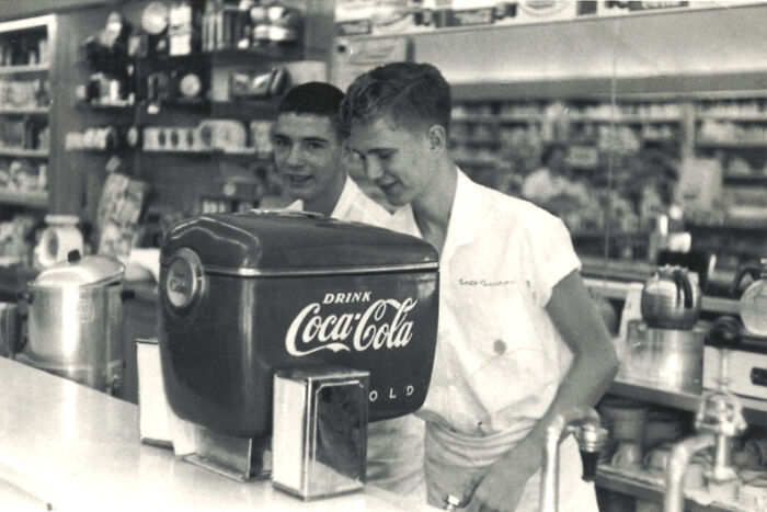 Two young boys at a vintage soda fountain counter with a classic Coca-Cola dispenser rare historical photograph.