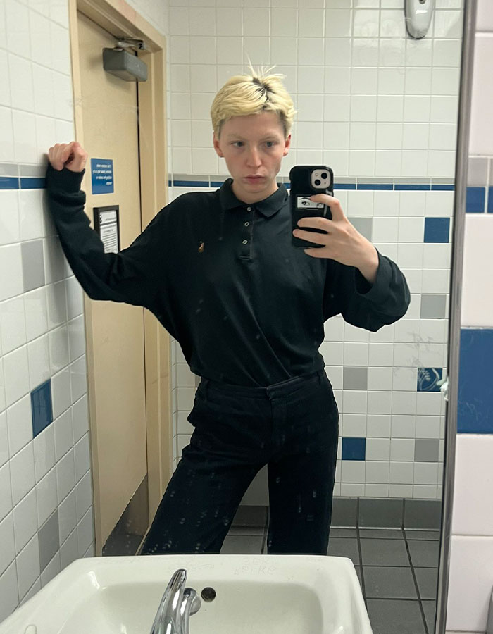 Young model taking a mirror selfie in a bathroom, reflecting on transition and detransition experiences. - 1