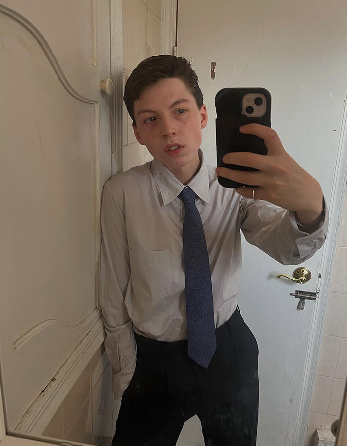 Model taking a mirror selfie wearing a shirt and tie, reflecting on detransition after transition at age 15. - 8