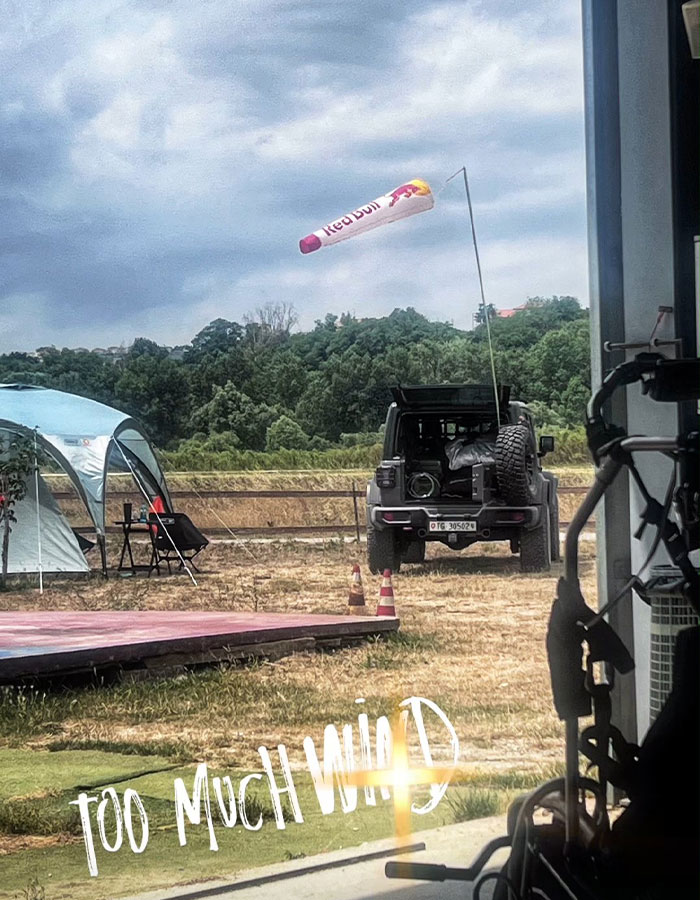 View of a windy outdoor area with a Red Bull windsock and the phrase too much wind displayed on the image View of a windy outdoor area with a Red Bull windsock and the phrase too much wind displayed on the image