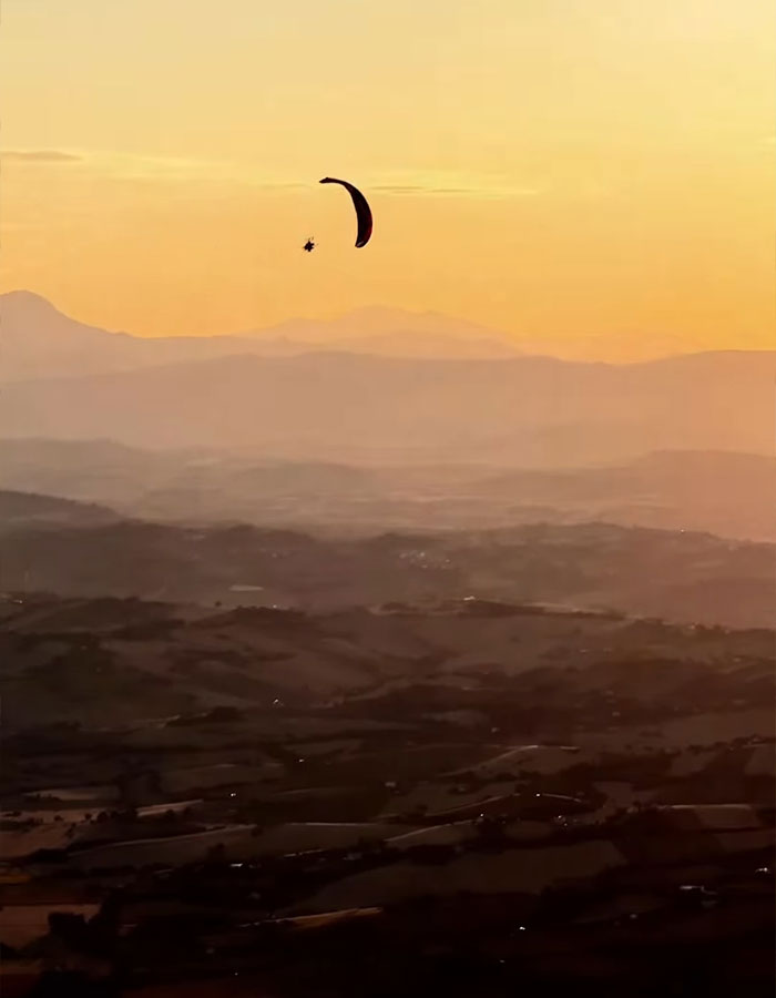 Skydiver soaring over hills at sunset, capturing the eerie final moments before the tragic mid-air incident. Skydiver soaring over hills at sunset, capturing the eerie final moments before the tragic mid-air incident.
