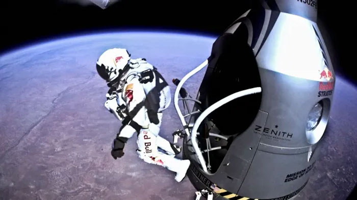 Daredevil skydiver in Red Bull suit exiting high-altitude capsule during extreme skydive over Earth’s curvature. Daredevil skydiver in Red Bull suit exiting high-altitude capsule during extreme skydive over Earth’s curvature.