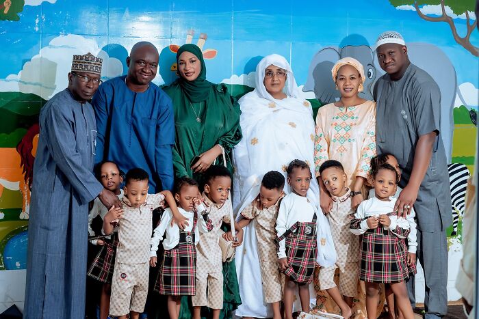 The world&rsquo;s first surviving nonuplets with family members posing together in front of a colorful mural