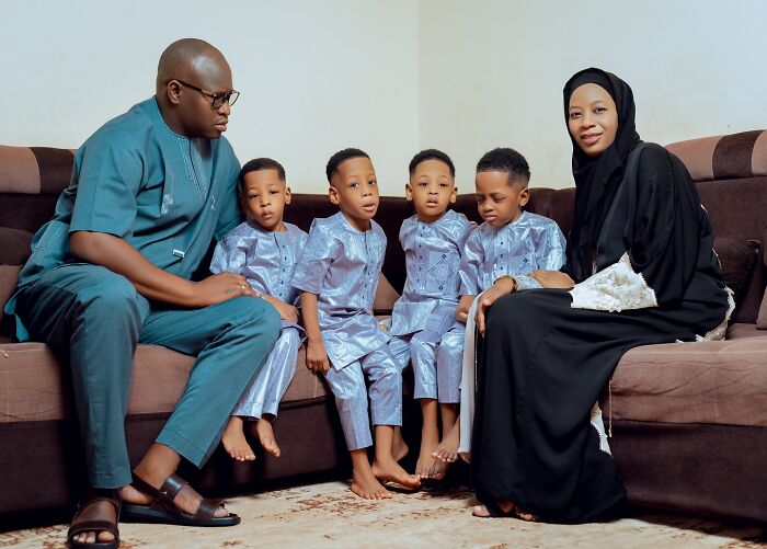 Parents sitting with four of the world&rsquo;s first surviving nonuplets, all boys dressed in matching traditional outfits at home.
