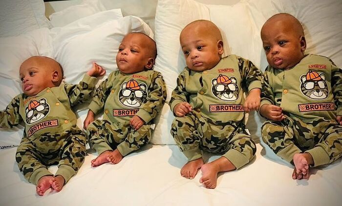 Four of the world&rsquo;s first surviving nonuplets wearing matching camo outfits, lying on a bed and growing up fast