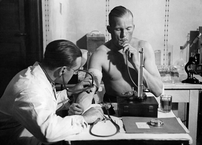 Doctor using unsettling medical devices from the past to measure a patient's lung function in a vintage clinical setting.