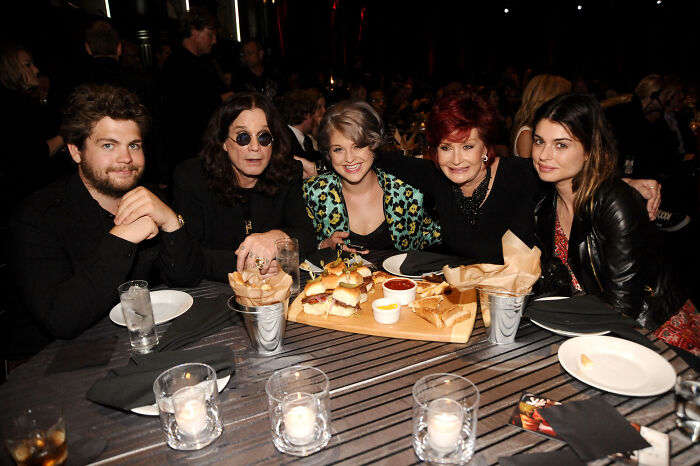 Ozzy Osbourne and family seated at a table with food, highlighting deep family rifts after kids were snubbed in tribute.