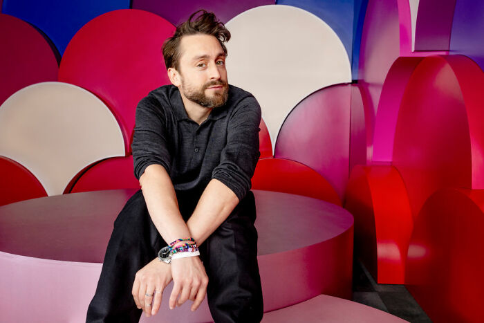 Man sitting thoughtfully on colorful abstract bench, representing celebrities who choose not to overspend despite wealth