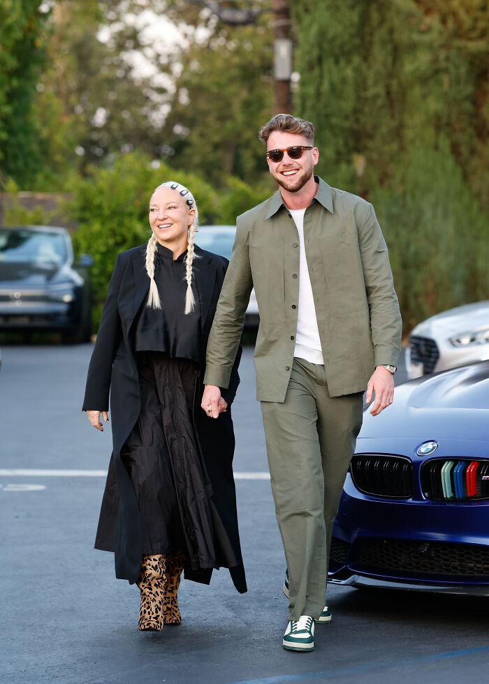 A model and Aussie star holding hands outdoors, smiling casually near parked cars, related to Netflix email campaign. A model and Aussie star holding hands outdoors, smiling casually near parked cars, related to Netflix email campaign.