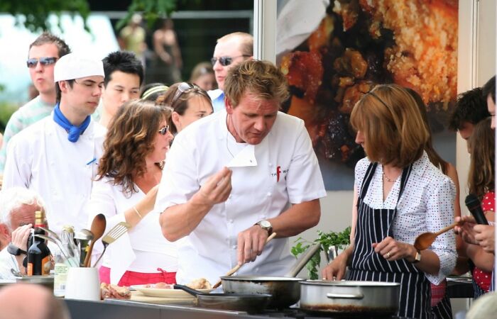 Celebrity chef cooking outdoors with a group, demonstrating skills and discussing the journey from poverty to super wealthy.