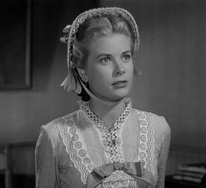 Black and white portrait of a woman in vintage lace dress and bonnet, evoking Grace Kelly&rsquo;s granddaughter legendary look revival.