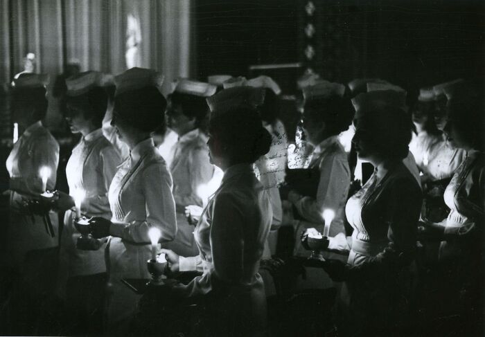 Vintage nurses holding candles in a ceremonial setting, reflecting hope and healing during a historical moment.