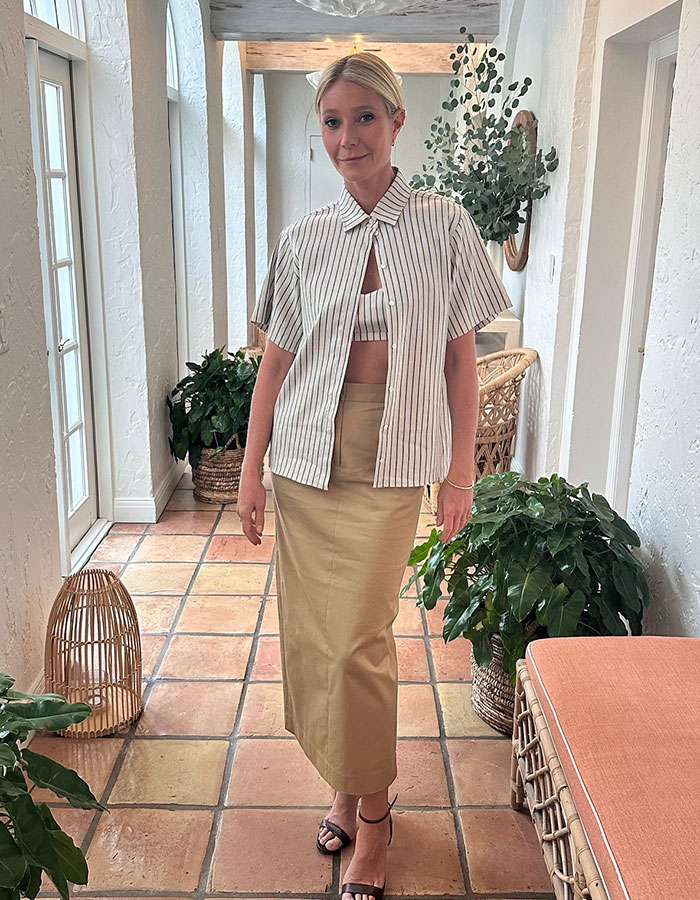 Gwyneth Paltrow posing indoors in a striped shirt and beige skirt amid plants and natural light, related to Coldplay frontman drama. Gwyneth Paltrow posing indoors in a striped shirt and beige skirt amid plants and natural light, related to Coldplay frontman drama.