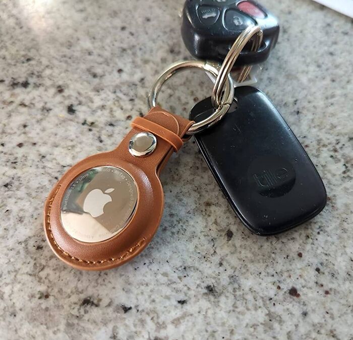 Keychain with Apple AirTag and Tile tracker attached to car keys, essential travel drama solutions for easy tracking and security.
