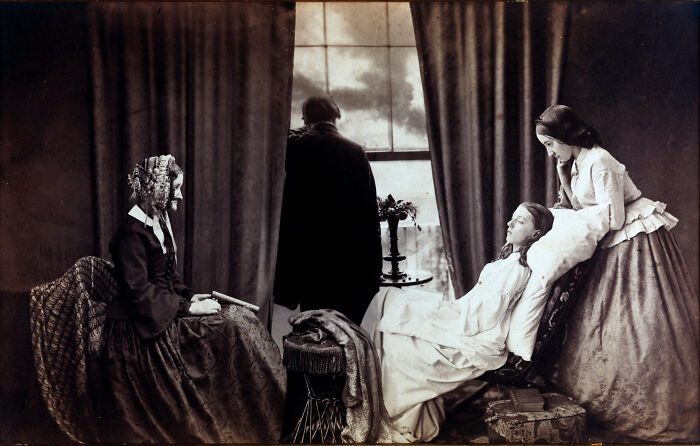 19th century invaluable photo showing a woman reclining with others around her in a historic indoor setting.